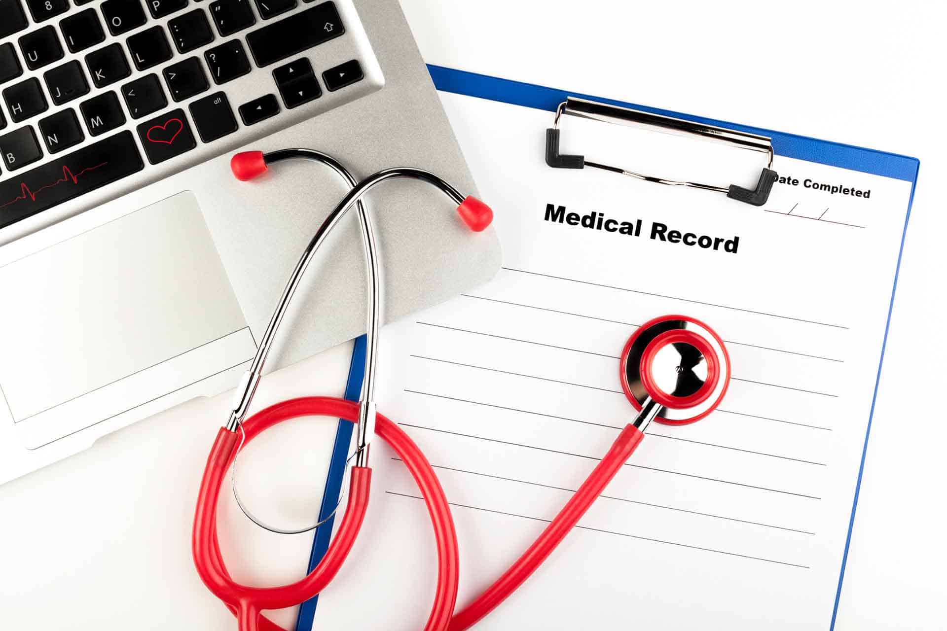 stethoscope and laptop on medical records